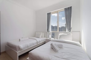 A modern hotel room with two single beds, a large window with curtains, and a view of the cityscape. - A Free Housekeeping Visit FOR Every Stay Between THE 16th FEB AND THE 16th MAR - Stayshort - Spacious 2 Bedroom in Dubai Marina That Sleeps 6 (Dubai)