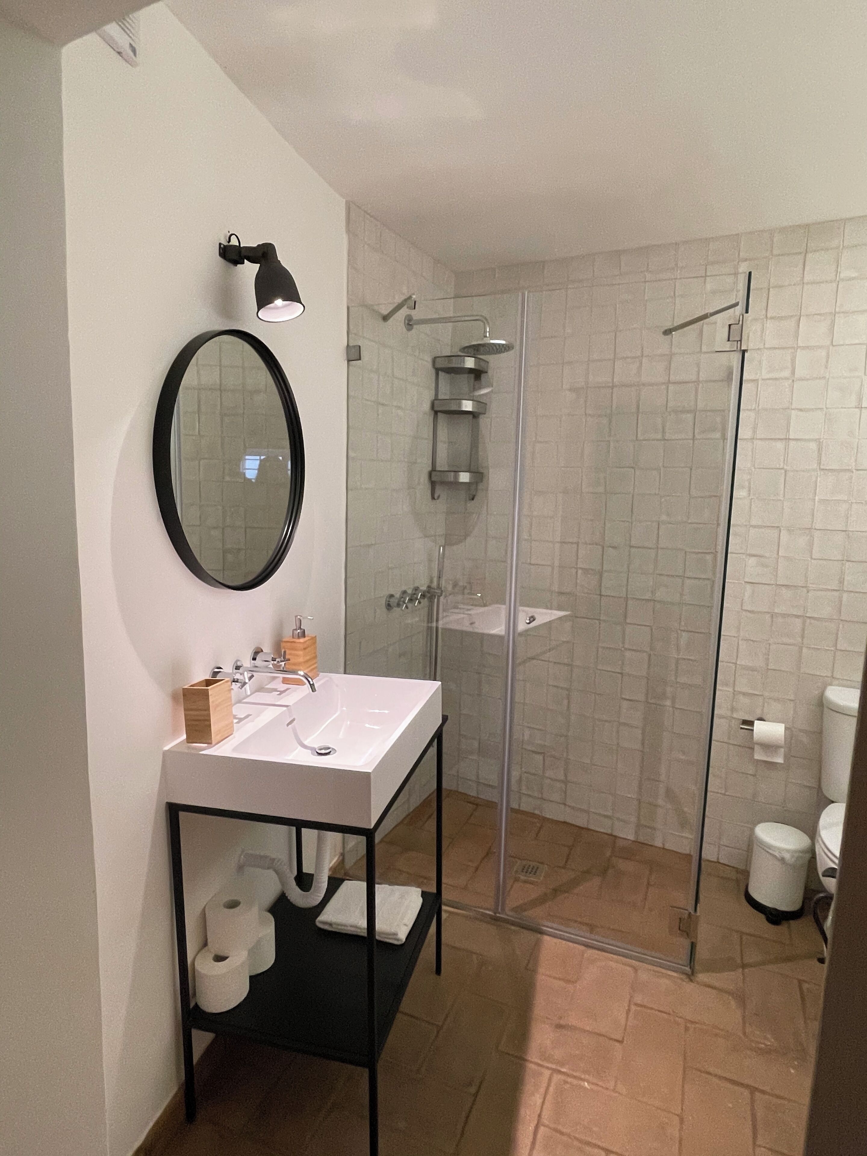 A modern bathroom with a glass-enclosed shower, a white sink with a black countertop, and a mirror above the sink.