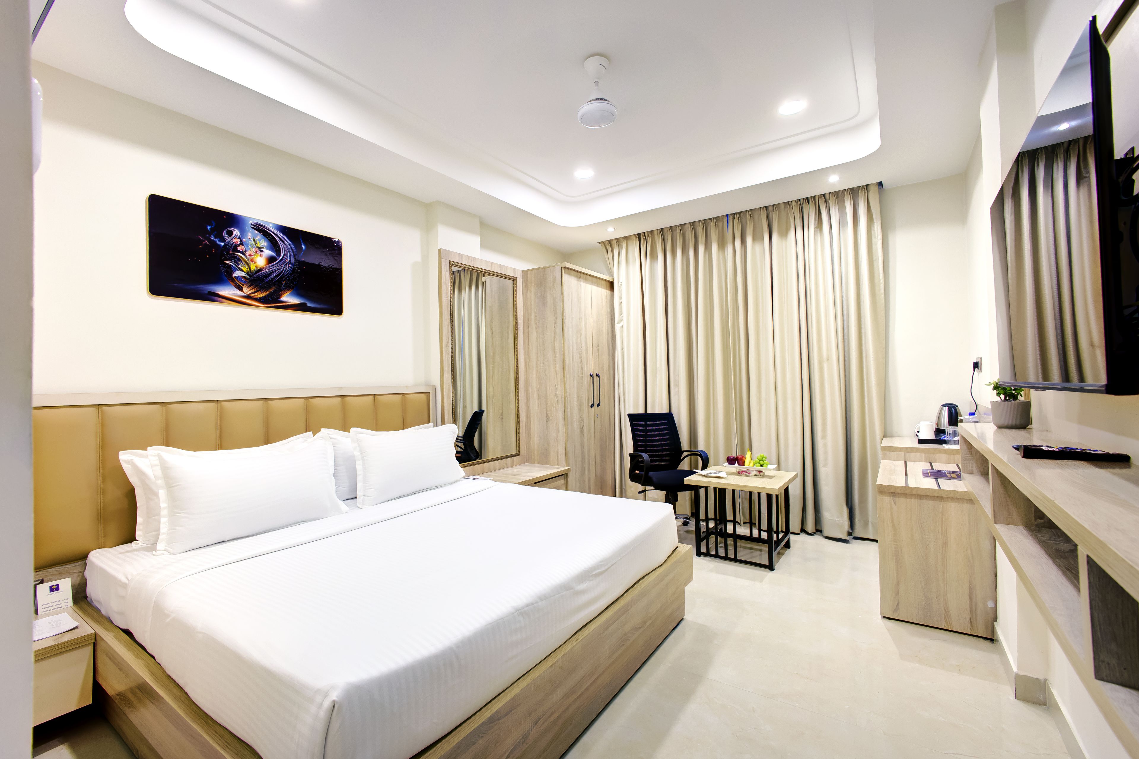A hotel room with a bed, a desk, a chair, a television, and a large window with curtains.