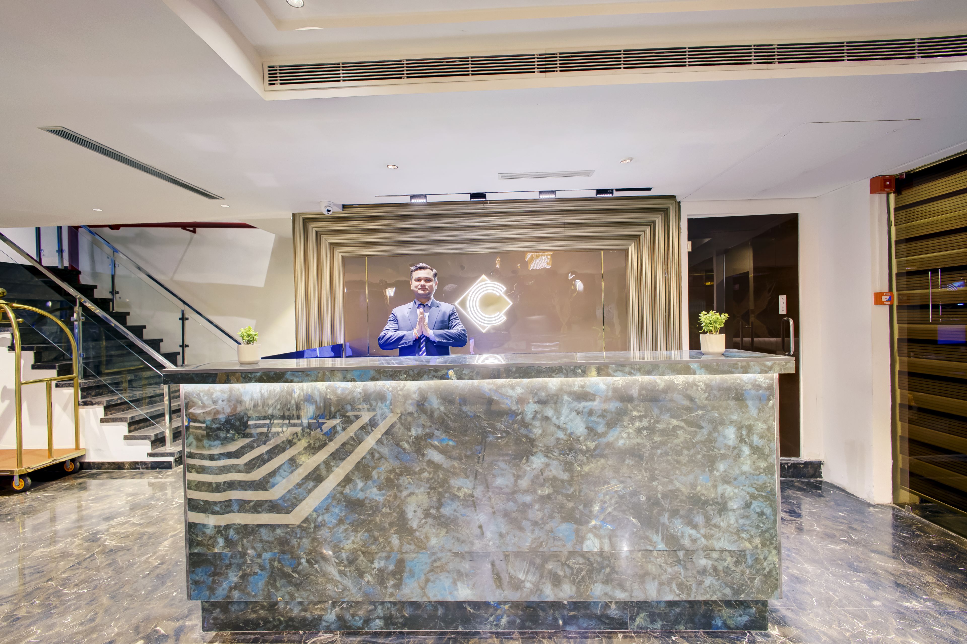 A reception desk with a marble top, a staircase to the left, and a closed shutter to the right.