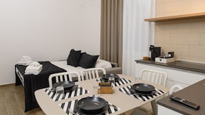 A compact hotel room with a bed, a dining table set for two, a kitchenette, and a small seating area. - L`Airone - Appartamento 2 (Campanarello)