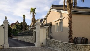 A gated entrance with stone walls and a paved driveway leading to a building with a stone facade and a barrel. - L`Airone - Appartamento 2 (Campanarello)