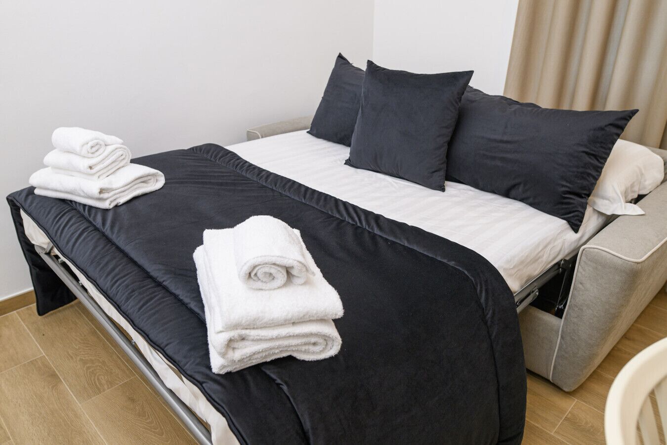 A neatly made bed with a black and white duvet, two pillows, and two folded white towels on the side.