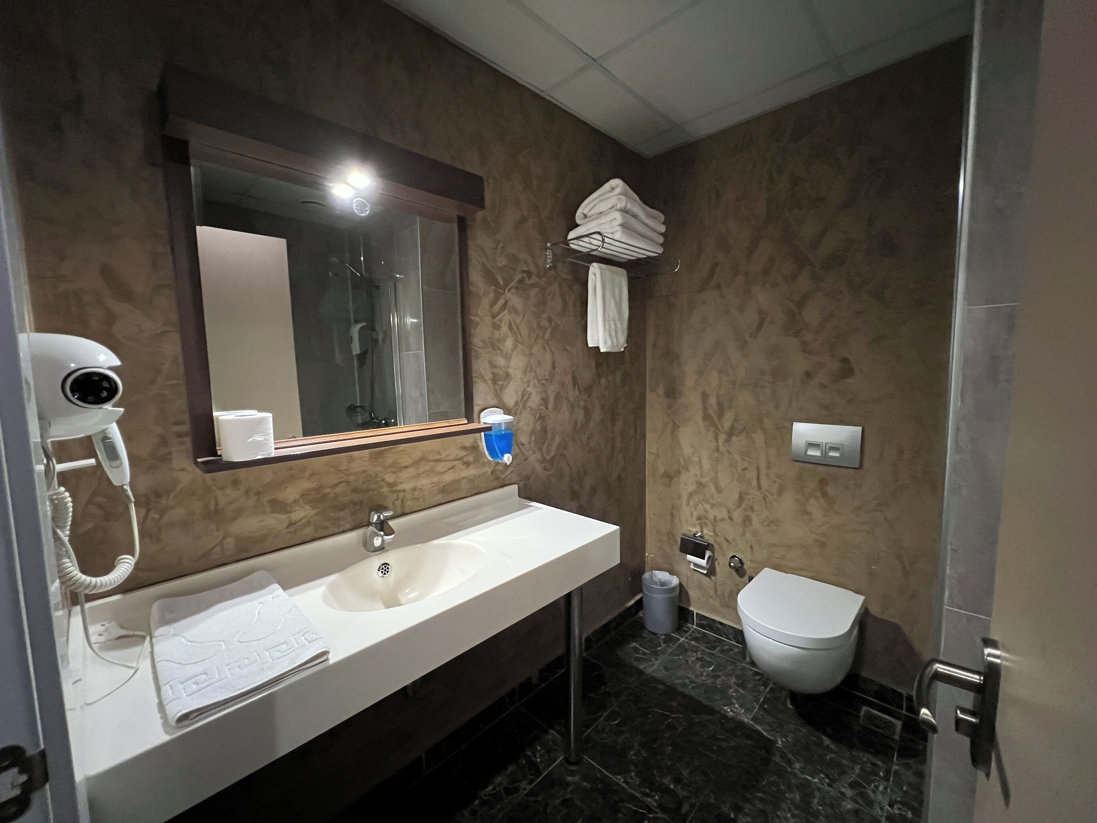 A bathroom with a sink, mirror, towel rack, and toilet.