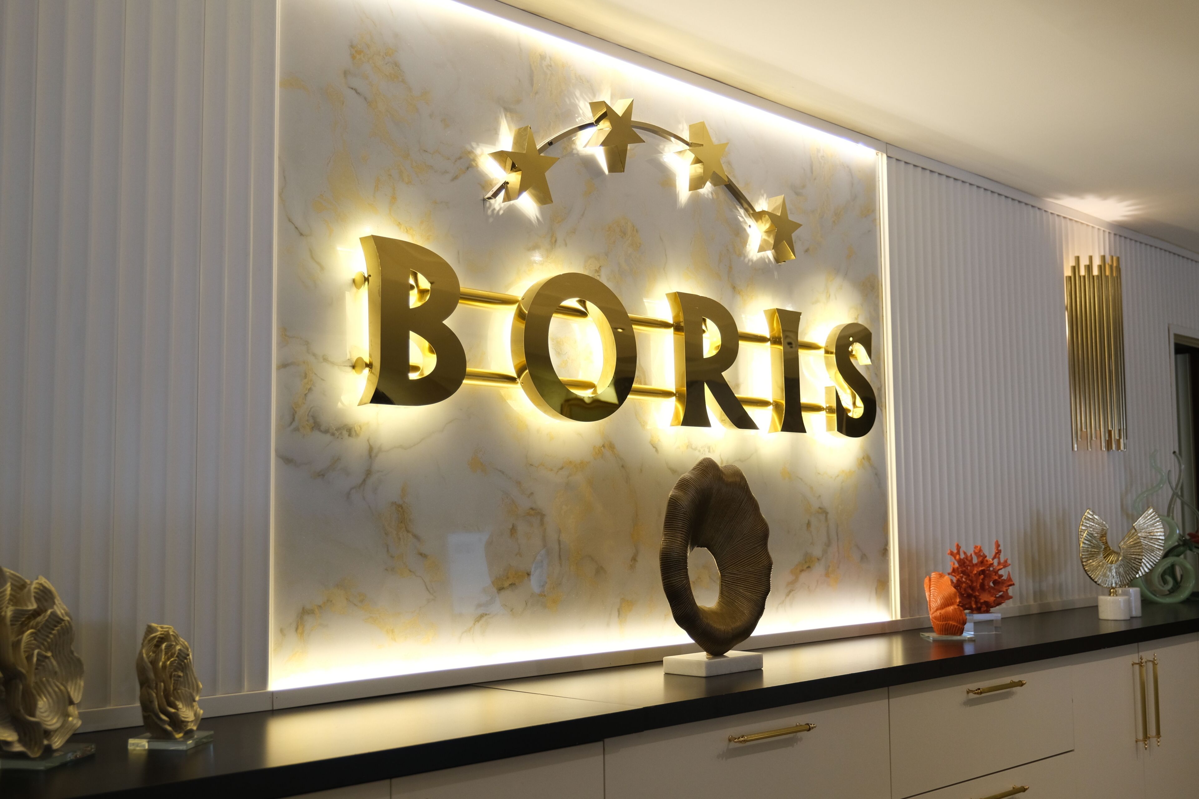 Una pared con letras iluminadas que deletrean 'BORIS' y un objeto decorativo debajo.