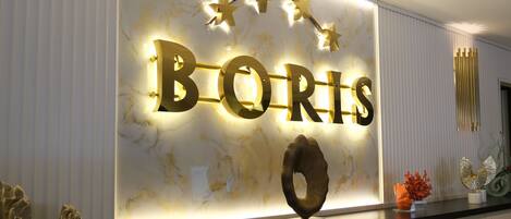 Una pared con letras iluminadas que deletrean 'BORIS' y un objeto decorativo debajo.