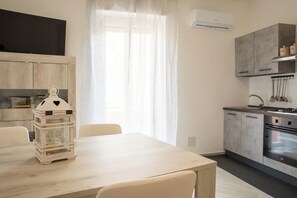 A modern kitchen with grey cabinets, a stainless steel sink, and an oven. There is a dining table with chairs and a decorative lantern. - Apartments The Three Moons-Full Moon (Alghero)