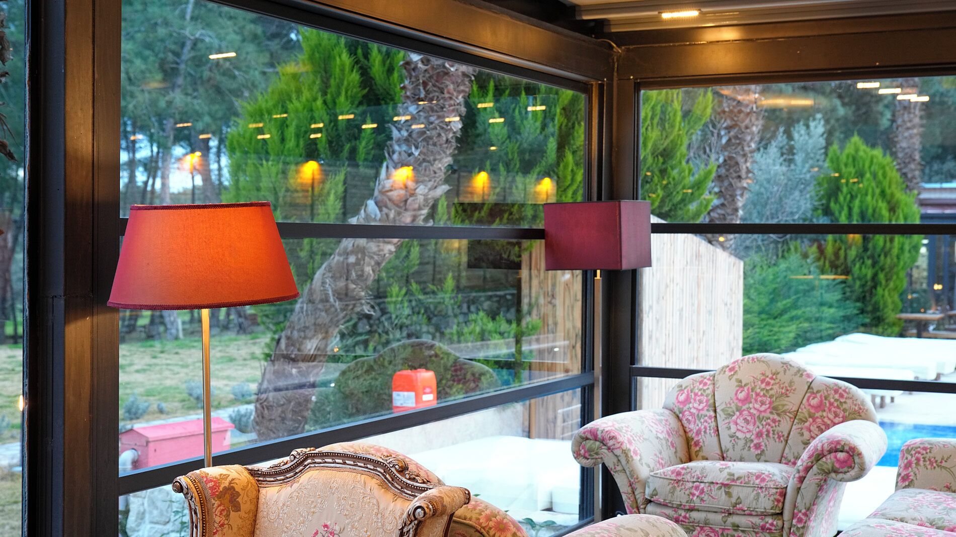 A room with large windows, two lamps, and a floral armchair.