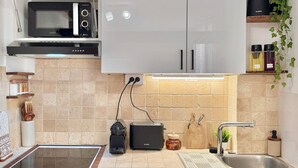 Een compacte keuken met een ingebouwde magnetron, broodrooster en kleine koelkast.