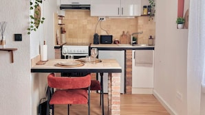 Een moderne keuken met witte kasten, een ingebouwde kookplaat en een eethoek met rode stoelen.