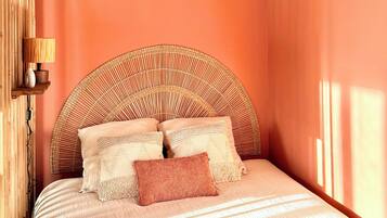 A bedroom with a bed, pillows, a lamp, and a wall-mounted shelf.
