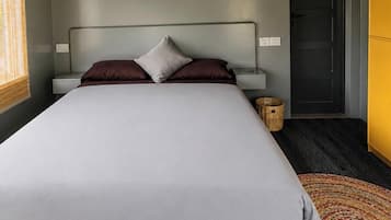 A bedroom with a bed, bedside tables, a ceiling fan, a door, and a window with blinds.