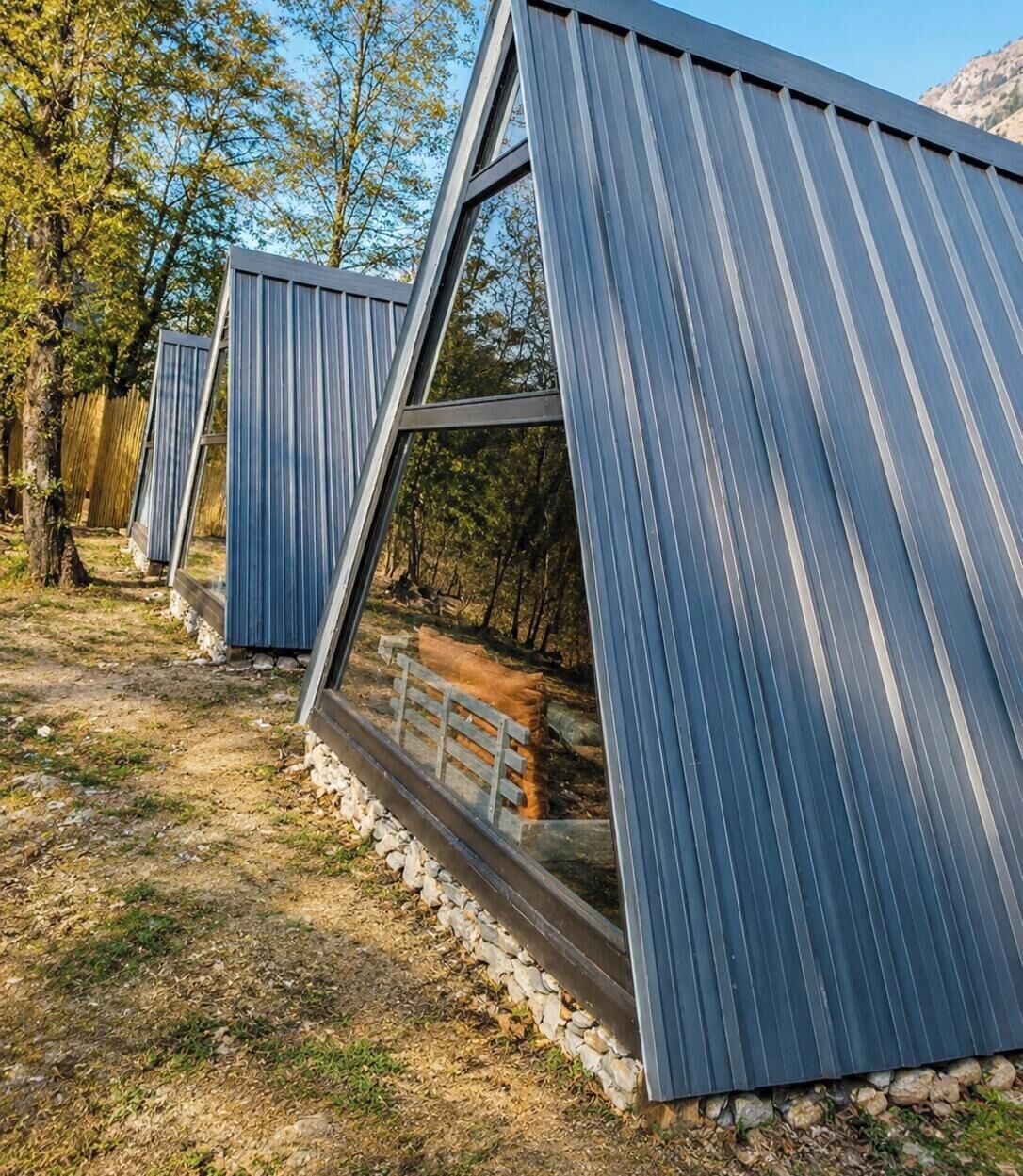 A series of modern, triangular structures with metal roofs, surrounded by a natural landscape.