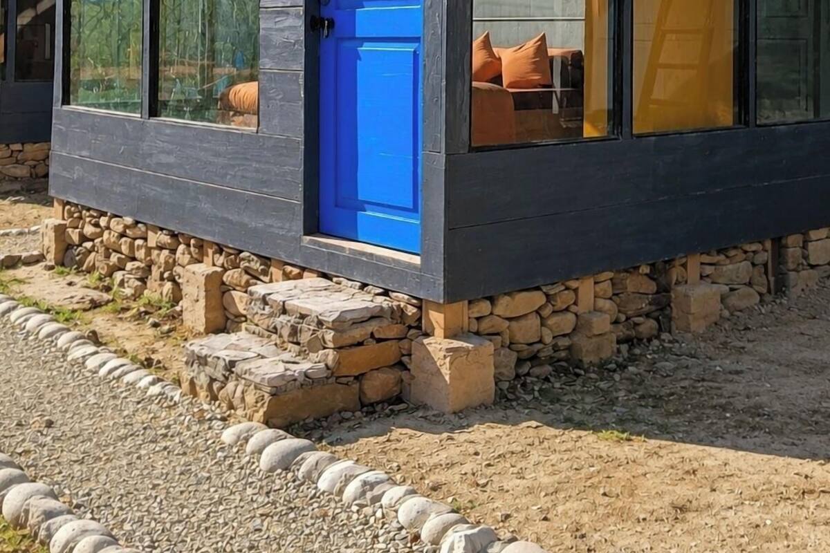A modern building with a blue door, large windows, and a stone foundation.