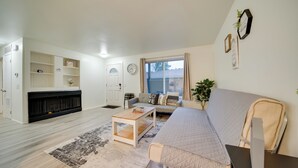 Ein modernes Wohnzimmer mit Sofa, Couchtisch, Kamin und einem großen Fenster.