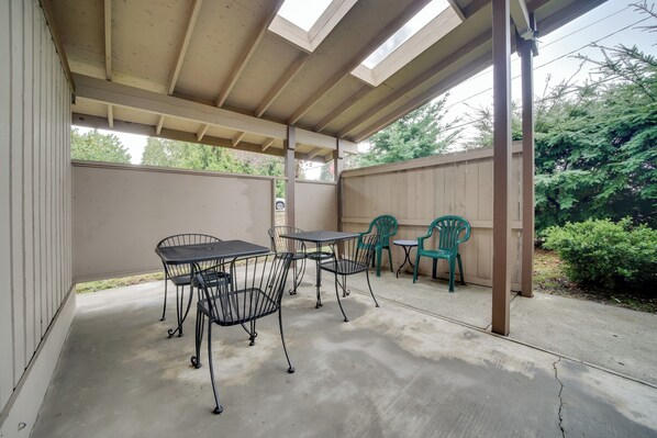 A covered patio area with a concrete floor, metal tables and chairs, and a wooden fence. - Duplex Group Getaway 3 Mi to Dtwn Bellevue! (Bellevue)