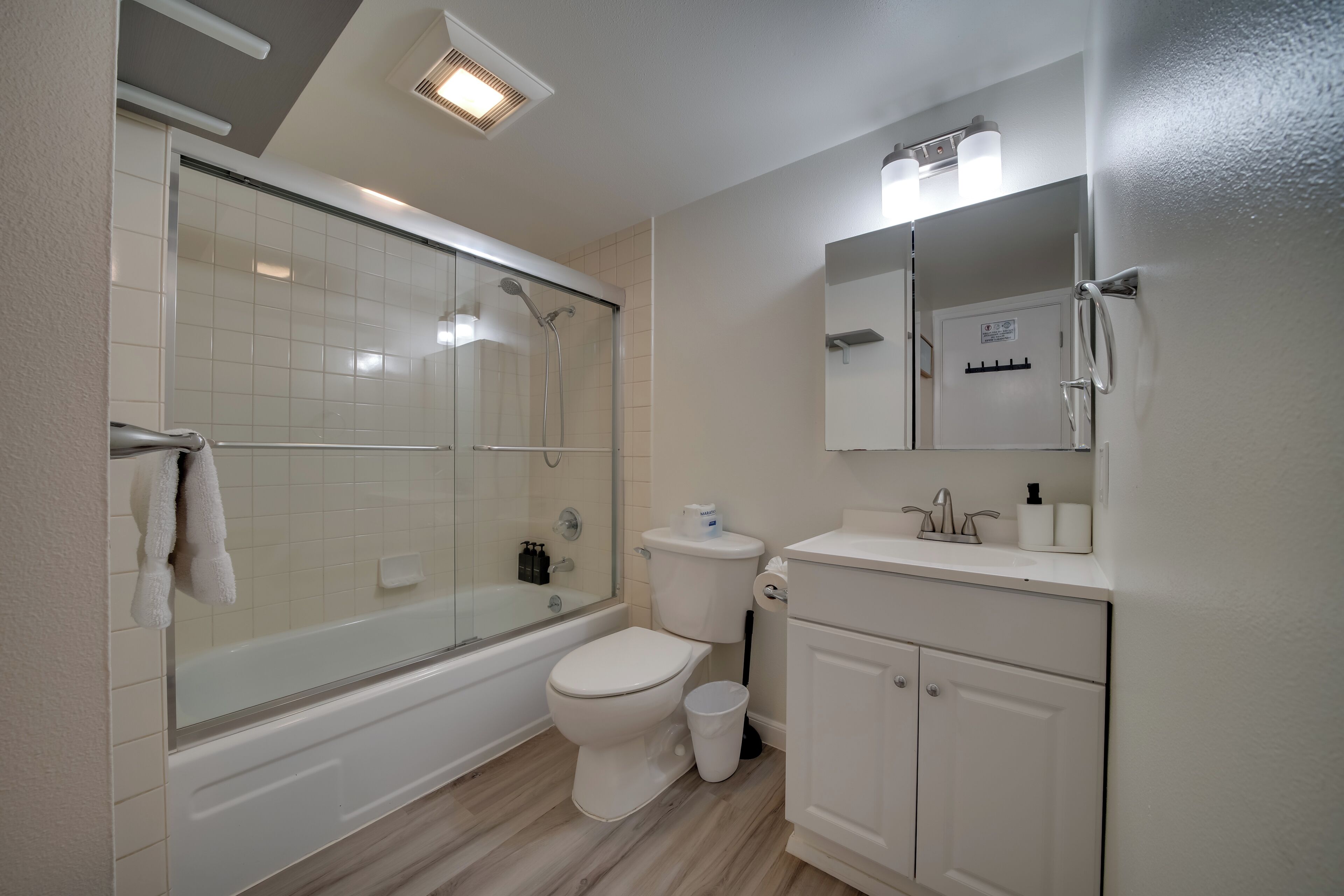 Un baño moderno con ducha de vidrio, inodoro y tocador con espejo.