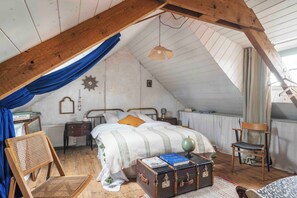 A cozy attic bedroom with a sloped ceiling, a wooden bed, a chair, a suitcase, and a globe. - Cozy artist and fisherman cottage by the sea in St-Suliac village by Saint-Malo (Saint-Suliac)