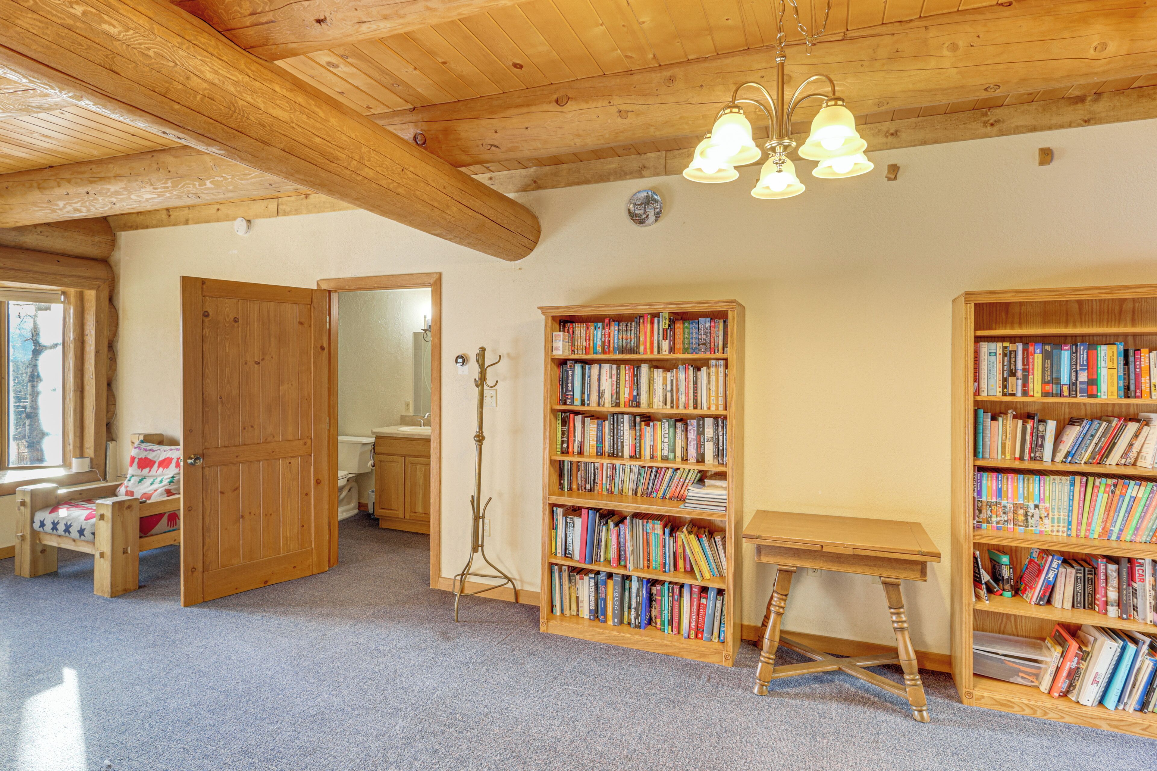 A cozy room with wooden bookshelves, a wooden desk, and a bed with a red and white patterned bedspread.