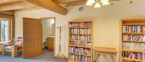 A cozy room with wooden bookshelves, a wooden desk, and a bed with a red and white patterned bedspread.