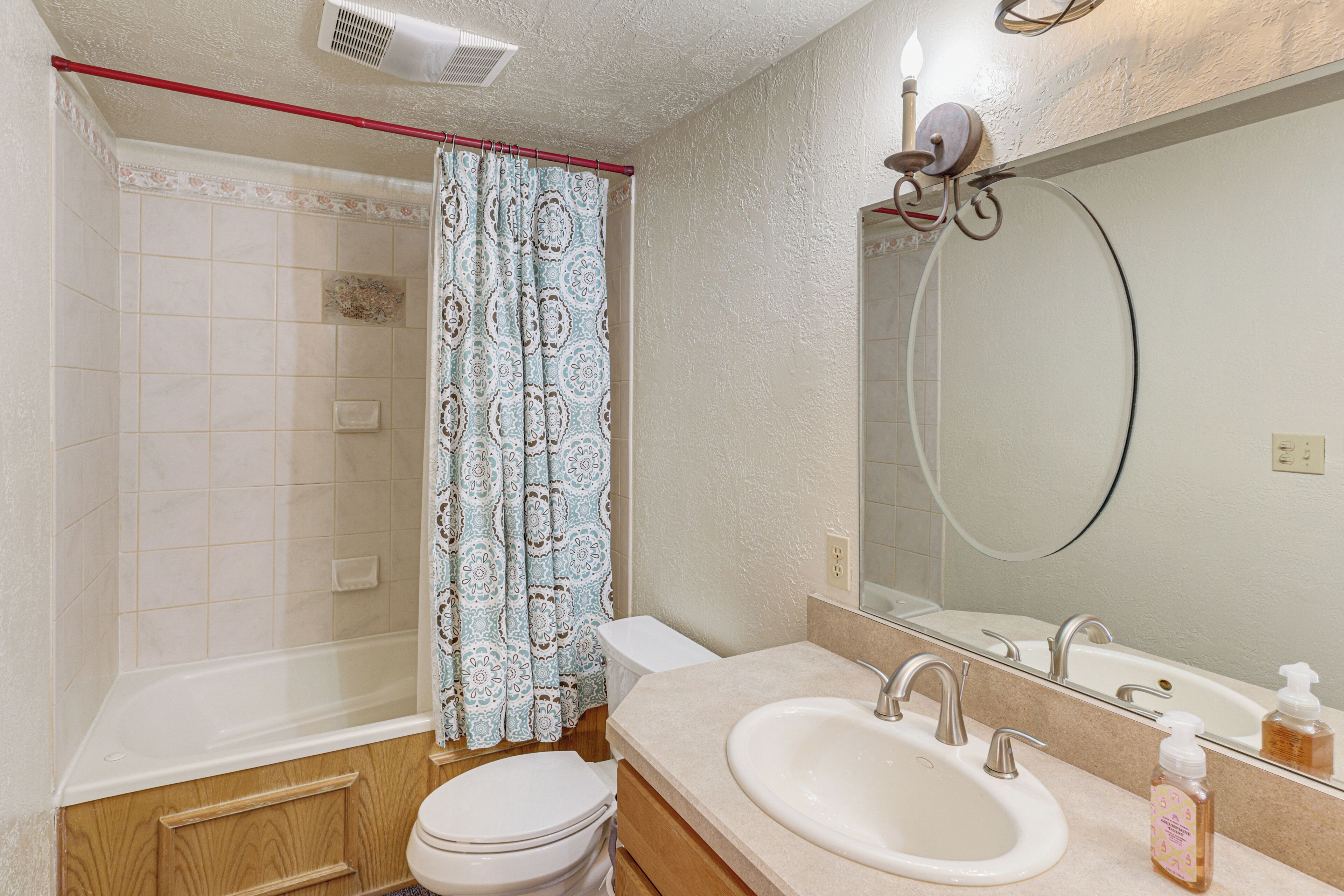Un baño con bañera, inodoro, lavabo y un espejo grande.