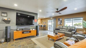 A spacious living room with a large flat-screen TV, leather sofas, a wooden coffee table, and a ceiling fan. - Private Outdoor Oasis! Chandler Home, 5 Mi to Dtwn (Chandler)