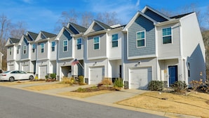 Une rangée de maisons de ville avec des garages attenants, une allée et une vue sur la rue.