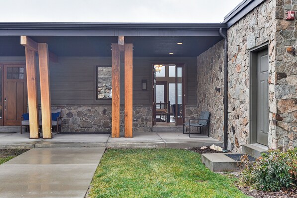 A stone building with a covered porch, wooden pillars, and a door with glass panels. - Luxe Eden Gem w/ Hot Tub: 6 Mi to Powder Mountain! (Eden)