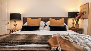 A neatly made bed with a brown and white duvet, two side tables with lamps, a framed picture on the wall, and a potted plant on the nightstand. - < 1 Mi to Georgetown Square: Pet-friendly Getaway! (Georgetown)