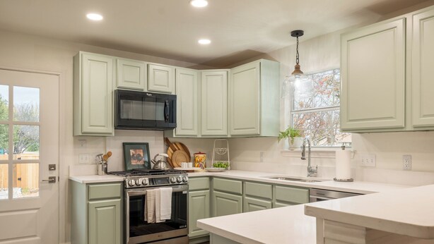 A kitchen with light green cabinets, a stainless steel stove, a microwave, and a window with a view of trees. - < 1 Mi to Georgetown Square: Pet-friendly Getaway! (Georgetown)