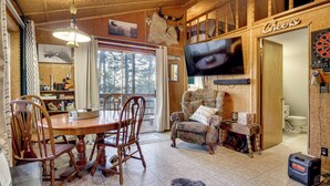 Ein Holzambiente mit Esstisch, Stühlen, Fernseher und Dartscheibe.