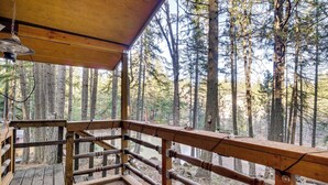 Eine Holzterrasse mit Geländer und Blick auf einen bewaldeten Bereich.