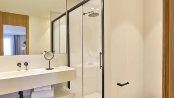 A modern bathroom with a glass-enclosed shower, a white sink with a mirror, and a toilet.