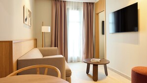 A hotel room with a bed, a sofa, a small table, a TV, and a window with curtains. -  Ocean Drive Málaga (Málaga)