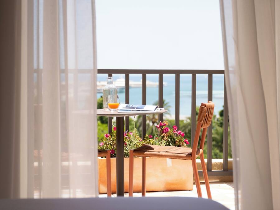 A balcony with a table, chair, and potted plants.