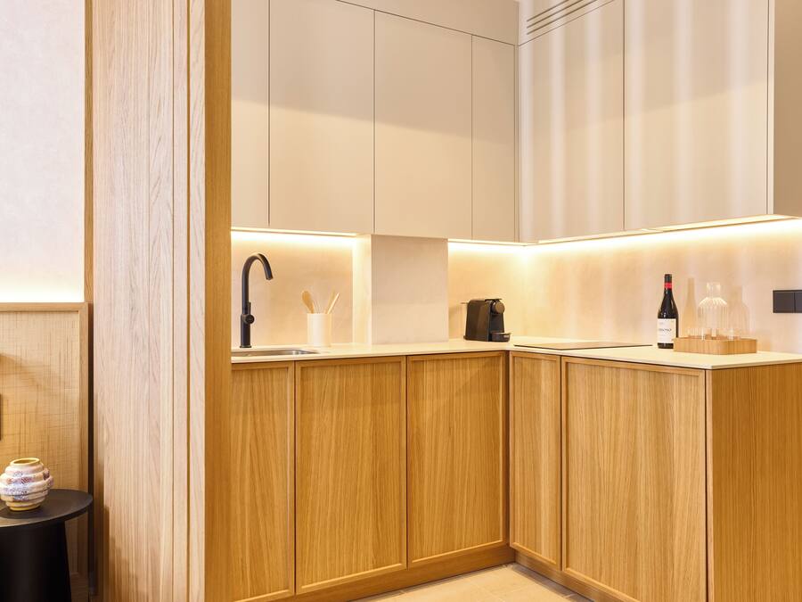 Cocina moderna con armarios de madera, un lavamanos de acero inoxidable y una encimera con una botella de vino y copas.