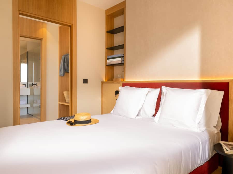 Une chambre d’hôtel avec un lit, une table de chevet, une armoire et une étagère remplie de livres.