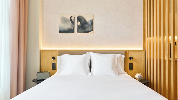 A hotel room with a large bed, two pillows, a nightstand with a lamp, and a wall-mounted artwork. -  Ocean Drive Málaga (Málaga)