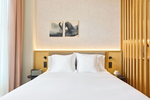 Une chambre d’hôtel avec un grand lit, deux oreillers, une table de chevet avec une lampe et une œuvre d’art accrochée au mur.
