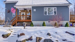 A two-story house with a wooden deck, a stone fireplace, and a snow-covered yard. - WFH Friendly! Quiet Greenville Home w/ Deck (Greenville)
