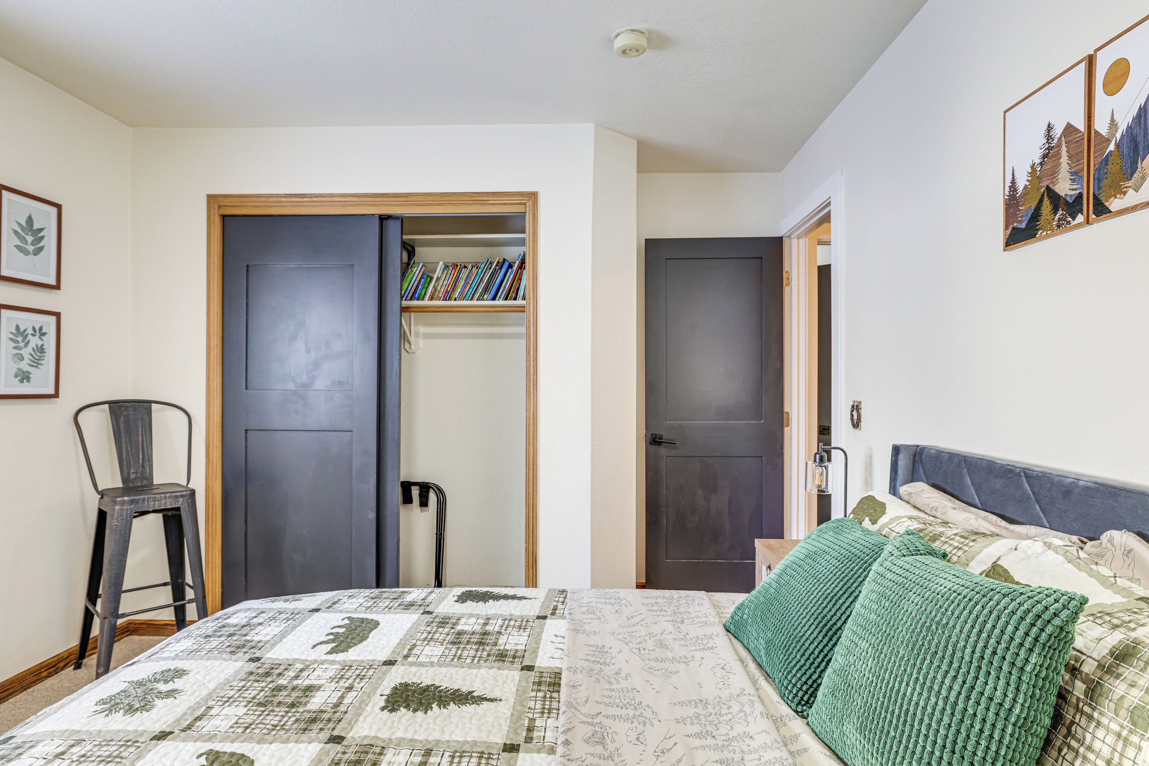 Ein Schlafzimmer mit Bett, Stuhl, Bücherregal und einer Tür.