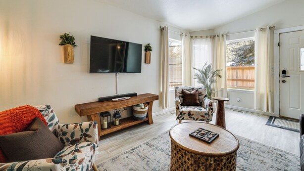 A living room with a flat-screen TV, a wooden bench, a patterned sofa, and a round coffee table. - Family Home w/ Game Room, 1 Mi to Lake Cascade! (Cascade)