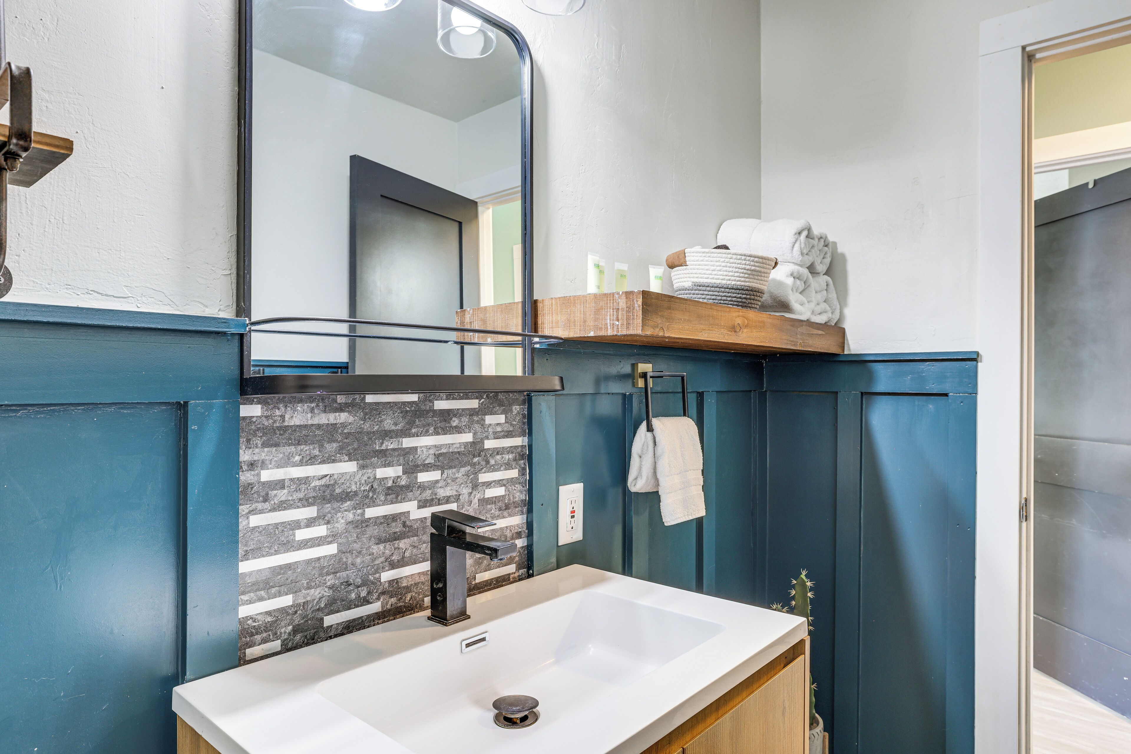 A bathroom with a white sink, a mirror, and a towel rack.