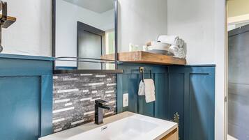 A bathroom with a white sink, a mirror, and a towel rack.