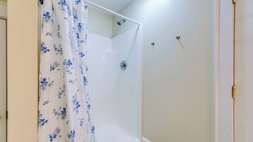 A shower area with a white shower curtain featuring blue floral patterns.
