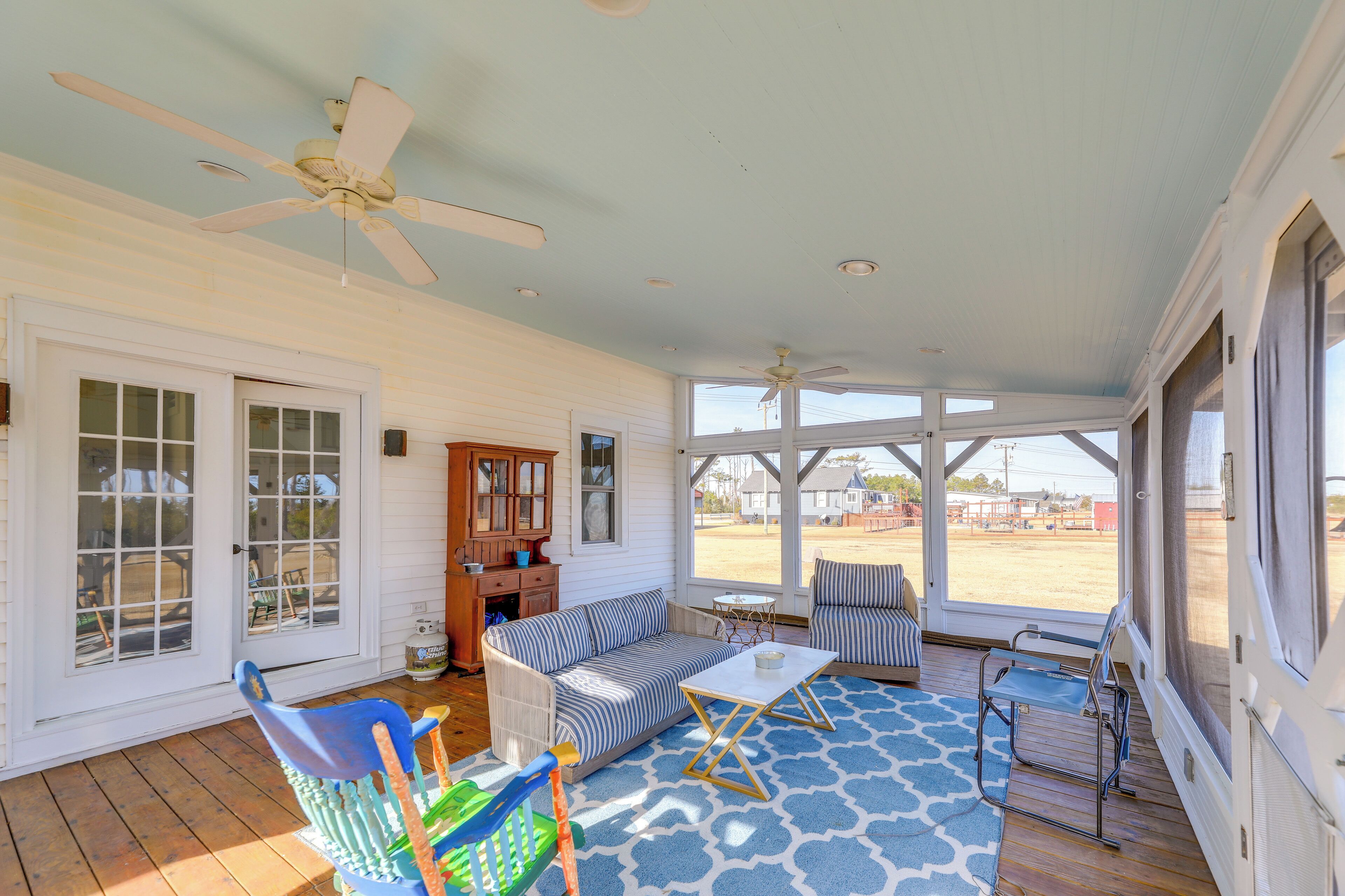 A covered porch with a sofa, chairs, and a table.