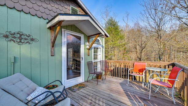 A wooden deck with outdoor furniture, a green building with a scalloped roof, and a clear sky. - Hike, Swim & Fish On-site: Blue Ridge Mtn Getaway (Thurmond)
