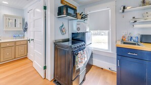 Une cuisine équipée d’une cuisinière, d’un four et d’un four à micro-ondes. Une fenêtre offre une vue sur l’extérieur.