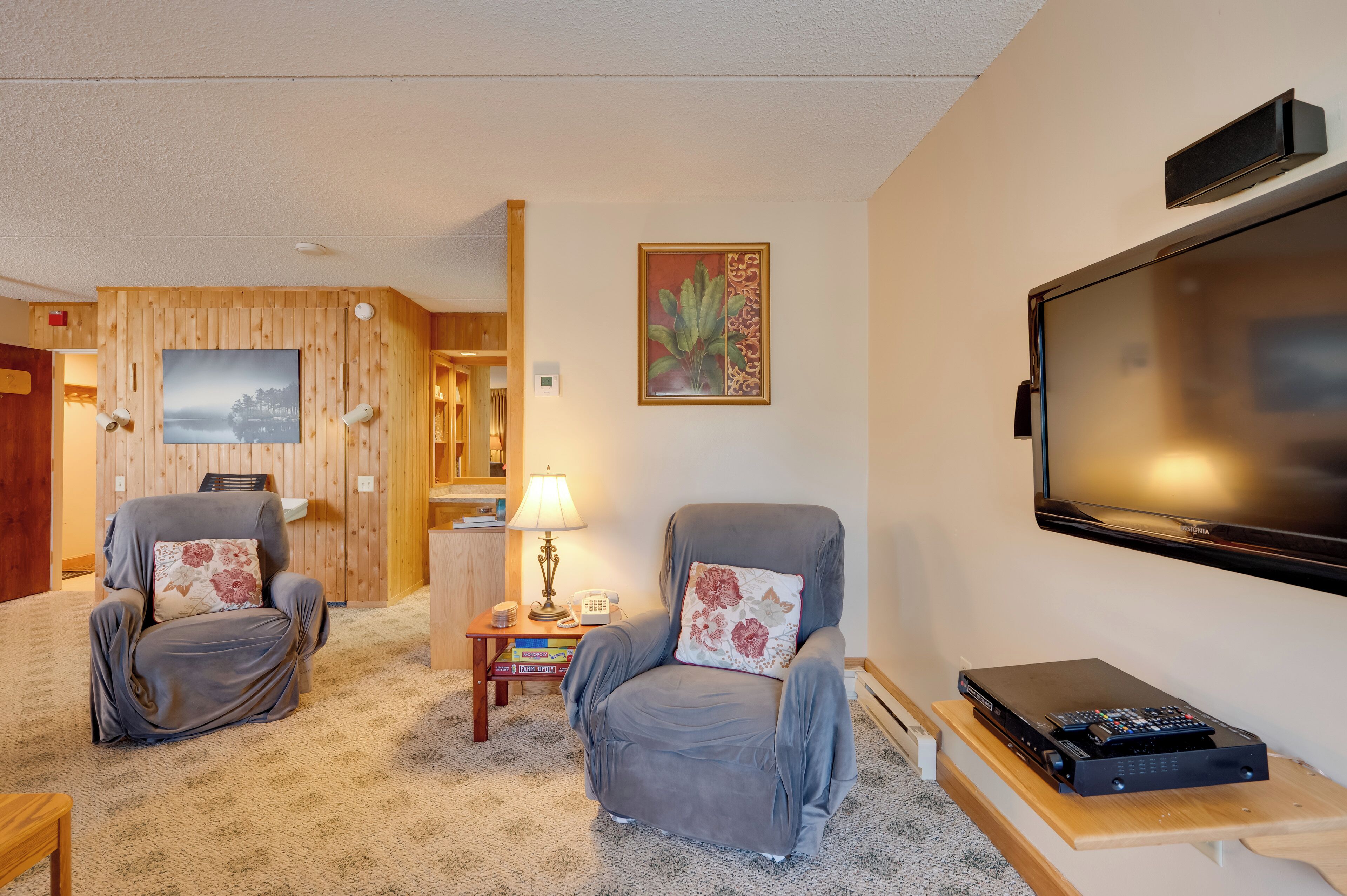 Ein Wohnzimmer mit zwei grauen Sesseln, einem Fernseher und einer Stereoanlage.