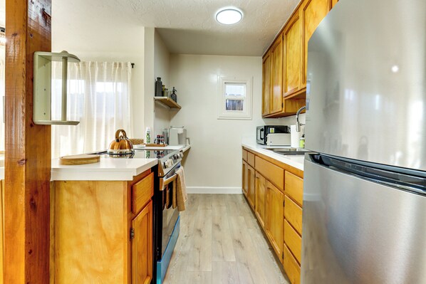 A compact kitchen with wooden cabinets, a stainless steel refrigerator, and a built-in oven. - Clear Lake Living! Pet-friendly Gem w/ Fenced Yard (Lakeport)